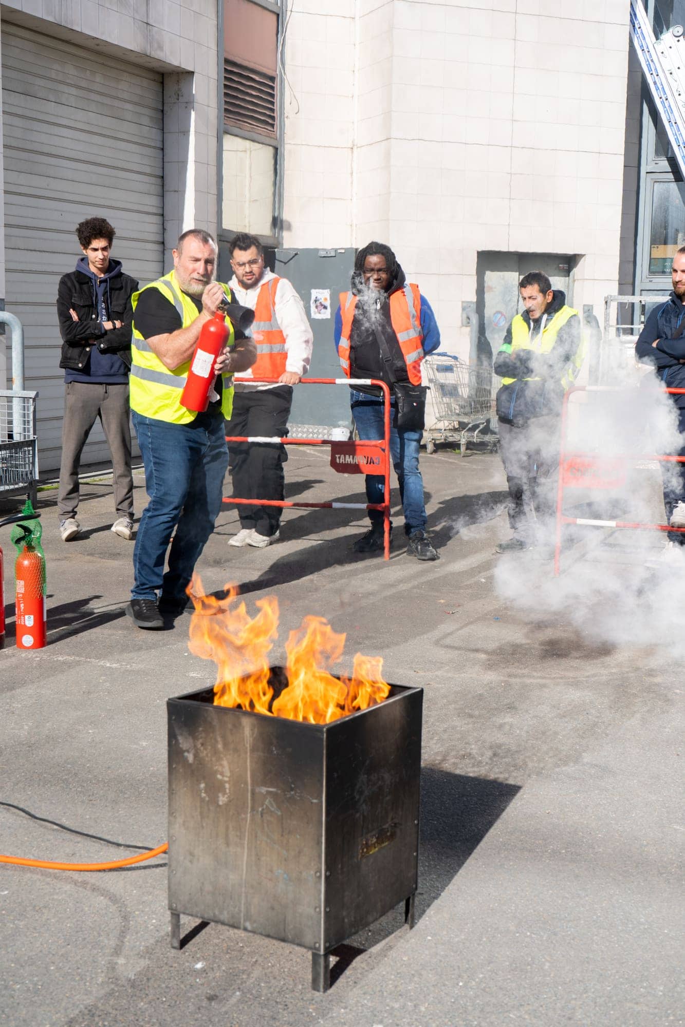 Stagiaire éteignant un feu réel dans un bac à feu lors d'une formation équipier de première intervention
