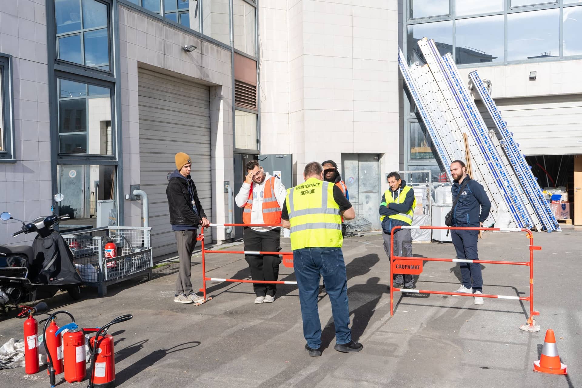 Groupe de stagiaires écoutant les consignes de sécurité avant un exercice incendie en extérieur