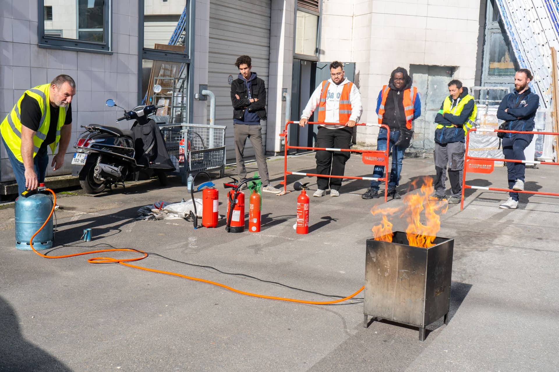 Formateur allumant le bac à feu au gaz devant un groupe de stagiaires en gilets